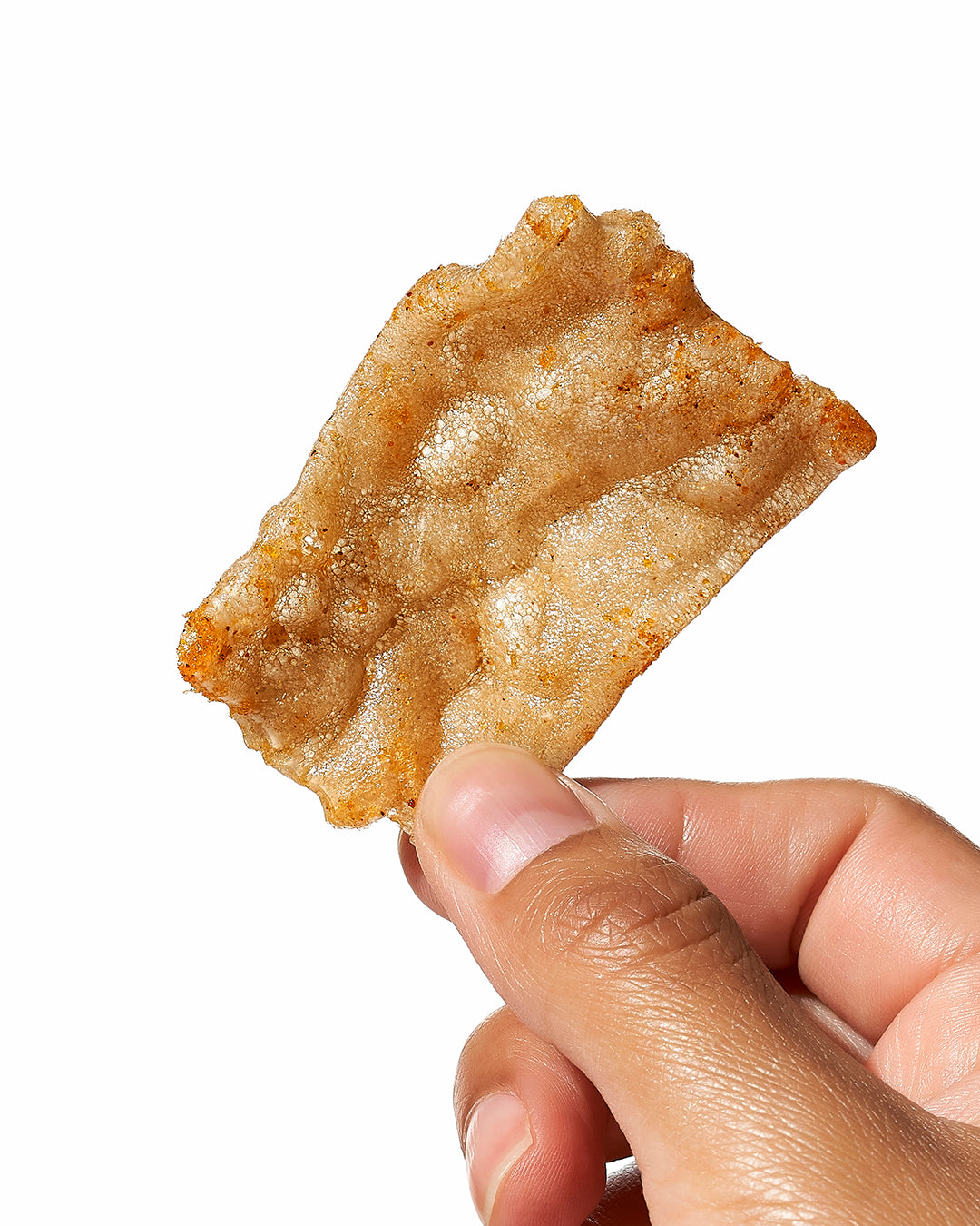 Single Snacklins chip held between fingers against a blurred background